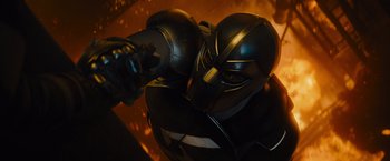 Movie still from “Samaritan” (2022), directed by Julius Avery – A person wearing a black and gold costume holding a gun; Medium shot, Low angle