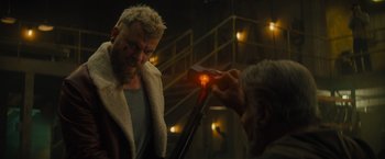 Movie still from “Samaritan” (2022), directed by Julius Avery – A man is lighting a candle on a man's face; Medium shot, Low angle