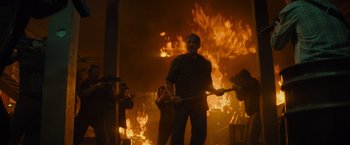 Movie still from “Samaritan” (2022), directed by Julius Avery – A group of people standing in front of a burning building; Medium shot, Low angle