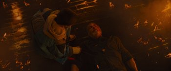Movie still from “Samaritan” (2022), directed by Julius Avery – An older man laying on the ground next to a younger man; Medium shot, Overhead angle