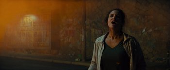 Movie still from “Samaritan” (2022), directed by Julius Avery – A woman standing on the side of the street; Medium shot, Low angle