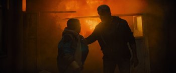 Movie still from “Samaritan” (2022), directed by Julius Avery – Two men are shaking hands in front of an orange sky; Medium shot, Low angle