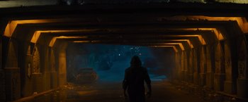 Movie still from “Samaritan” (2022), directed by Julius Avery – A man in a hooded jacket walking through a tunnel; Wide shot, Over the shoulder angle