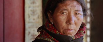 Movie still from “Samsara” (2011), directed by Ron Fricke – An older woman wearing a red and black scarf; Extreme Close Up shot, High angle