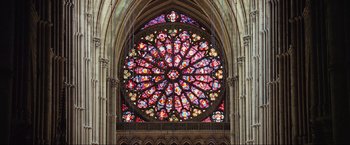 Movie still from “Samsara” (2011), directed by Ron Fricke – A stained - glass window in a cathedral with a large circular window; Extreme Wide shot, Overhead angle