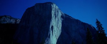 Movie still from “Samsara” (2011), directed by Ron Fricke – A large rock face with a blue sky in the background; Extreme Wide shot, Low angle