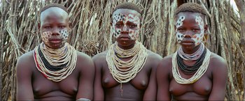 Movie still from “Samsara” (2011), directed by Ron Fricke – A group of people that are standing in the grass; Close Up shot, High angle