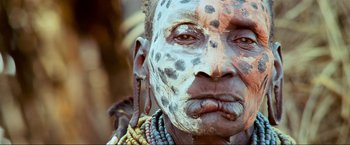 Movie still from “Samsara” (2011), directed by Ron Fricke – A man with a leopard pattern face paint; Extreme Close Up shot, Over the shoulder angle