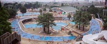 Movie still from “Samsara” (2011), directed by Ron Fricke – An aerial view of an outdoor pool with people swimming and playing in it; Extreme Wide shot, High angle