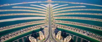 Movie still from “Samsara” (2011), directed by Ron Fricke – An aerial view of a large city with palm jumeirah in the background; Extreme Wide shot, Overhead angle