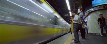 Movie still from “Samsara” (2011), directed by Ron Fricke – People waiting for a train at a train station; Wide shot, Low angle