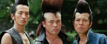 Movie still from “Samsara” (2011), directed by Ron Fricke – A man with a very large mohawk on top of his head; Close Up shot, Low angle