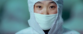 Movie still from “Samsara” (2011), directed by Ron Fricke – A person wearing a mask and a white coat; Extreme Close Up shot, Over the shoulder angle