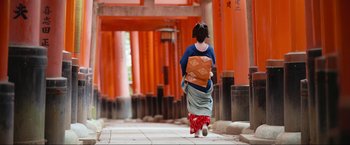 Movie still from “Samsara” (2011), directed by Ron Fricke – A woman walking down the street wearing a kimono; Wide shot, Low angle