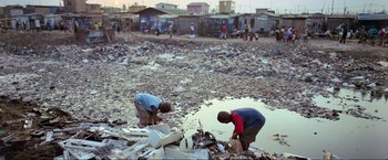 Movie still from “Samsara” (2011), directed by Ron Fricke – Two men are working in a trash pile in the dirt; Wide shot, High angle