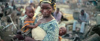 Movie still from “Samsara” (2011), directed by Ron Fricke – A woman and a baby are standing in a market place; Close Up shot, High angle