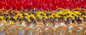 Movie still from “Samsara” (2011), directed by Ron Fricke – A large group of young people standing in a field; Extreme Wide shot, High angle