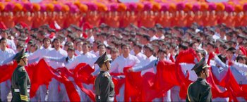 Movie still from “Samsara” (2011), directed by Ron Fricke – A group of people in red and white uniforms; Extreme Wide shot, High angle