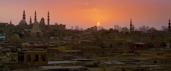 Movie still from “Samsara” (2011), directed by Ron Fricke – The sun is setting over a city with a lot of buildings; Extreme Wide shot, High angle
