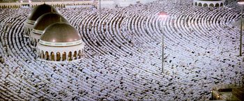 Movie still from “Samsara” (2011), directed by Ron Fricke – A large group of people standing in a room; Extreme Wide shot, Overhead angle