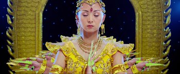 Movie still from “Samsara” (2011), directed by Ron Fricke – A woman in a yellow dress and a gold necklace; Close Up shot, Low angle