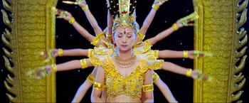 Movie still from “Samsara” (2011), directed by Ron Fricke – A woman in a yellow dress and a gold crown; Medium shot, Overhead angle