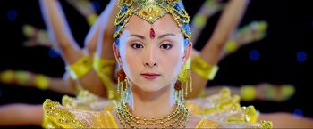 Movie still from “Samsara” (2011), directed by Ron Fricke – A woman in a yellow dress and a gold headpiece; Close Up shot, Low angle