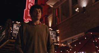 Movie still from “Big Time Adolescence” (2019), directed by Jason Orley – A man standing in front of a building at night; Medium shot, Low angle