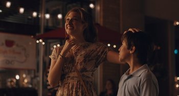 Movie still from “Big Time Adolescence” (2019), directed by Jason Orley – A young woman standing next to a young man in front of lights; Medium shot, Over the shoulder angle