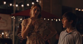 Movie still from “Big Time Adolescence” (2019), directed by Jason Orley – A woman in a floral dress standing next to a man; Medium shot, Over the shoulder angle