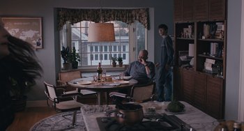Movie still from “Big Time Adolescence” (2019), directed by Jason Orley – Two men are sitting at a table in a kitchen; Wide shot, Over the shoulder angle