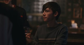 Movie still from “Big Time Adolescence” (2019), directed by Jason Orley – A young man holding a wine glass in his hand; Close Up shot, Over the shoulder angle
