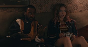 Movie still from “Big Time Adolescence” (2019), directed by Jason Orley – A man and a woman sitting next to each other on a couch; Medium shot, Over the shoulder angle