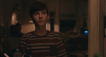 Movie still from “Big Time Adolescence” (2019), directed by Jason Orley – A young man in a striped shirt looking at the camera; Close Up shot, Over the shoulder angle