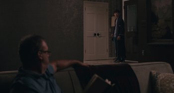 Movie still from “Big Time Adolescence” (2019), directed by Jason Orley – A man standing in front of a door in a room; Wide shot, Over the shoulder angle
