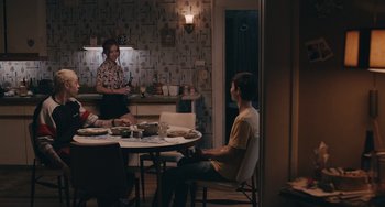Movie still from “Big Time Adolescence” (2019), directed by Jason Orley – Two people are sitting at a table in a kitchen; Wide shot, Over the shoulder angle