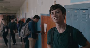 Movie still from “Big Time Adolescence” (2019), directed by Jason Orley – A young man standing in a hallway next to a bunch of lockers; Medium shot, Over the shoulder angle