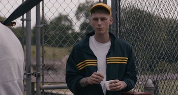 Movie still from “Big Time Adolescence” (2019), directed by Jason Orley – A man in a yellow hat is holding something; Close Up shot, Over the shoulder angle