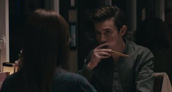 Movie still from “Big Time Adolescence” (2019), directed by Jason Orley – A man holding chopsticks in his mouth while looking at a woman; Close Up shot, Over the shoulder angle