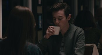 Movie still from “Big Time Adolescence” (2019), directed by Jason Orley – A man drinking a cup of coffee while sitting next to a woman; Close Up shot, Over the shoulder angle