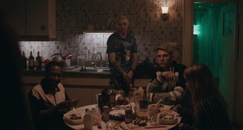Movie still from “Big Time Adolescence” (2019), directed by Jason Orley – A group of people sitting at a table eating food; Medium shot, Over the shoulder angle