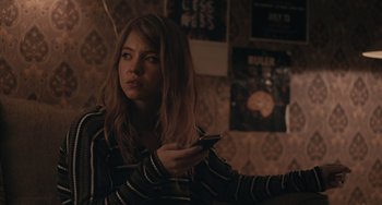 Movie still from “Big Time Adolescence” (2019), directed by Jason Orley – A woman holding a cell phone in her hand; Medium shot, Over the shoulder angle