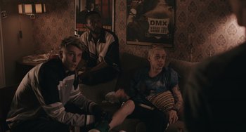 Movie still from “Big Time Adolescence” (2019), directed by Jason Orley – A group of young men sitting on top of couches; Medium shot, Over the shoulder angle