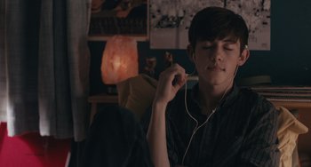 Movie still from “Big Time Adolescence” (2019), directed by Jason Orley – A young man is listening to music on his phone; Medium shot, High angle