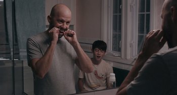 Movie still from “Big Time Adolescence” (2019), directed by Jason Orley – A man brushing his teeth in front of a mirror; Medium shot, Over the shoulder angle