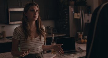 Movie still from “Big Time Adolescence” (2019), directed by Jason Orley – A woman standing in front of a laptop computer; Medium shot, Over the shoulder angle