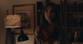 Movie still from “Big Time Adolescence” (2019), directed by Jason Orley – A woman standing in front of a lamp in a room; Close Up shot, Over the shoulder angle