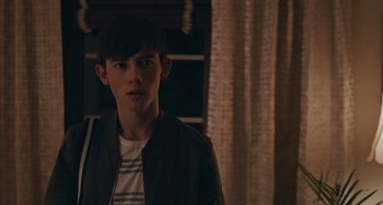 Movie still from “Big Time Adolescence” (2019), directed by Jason Orley – A young man standing in front of a window; Close Up shot, Over the shoulder angle