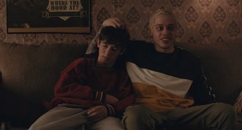 Movie still from “Big Time Adolescence” (2019), directed by Jason Orley – Two young men sitting on a couch next to each other; Medium shot, Over the shoulder angle
