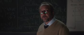 Movie still from “San Andreas” (2015), directed by Brad Peyton – A man with a goatee wearing glasses in front of chalkboards; Close Up shot, Over the shoulder angle